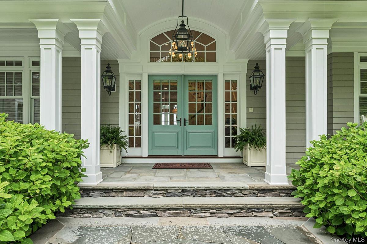Double door entry with blue stone walkways and covered area with seating