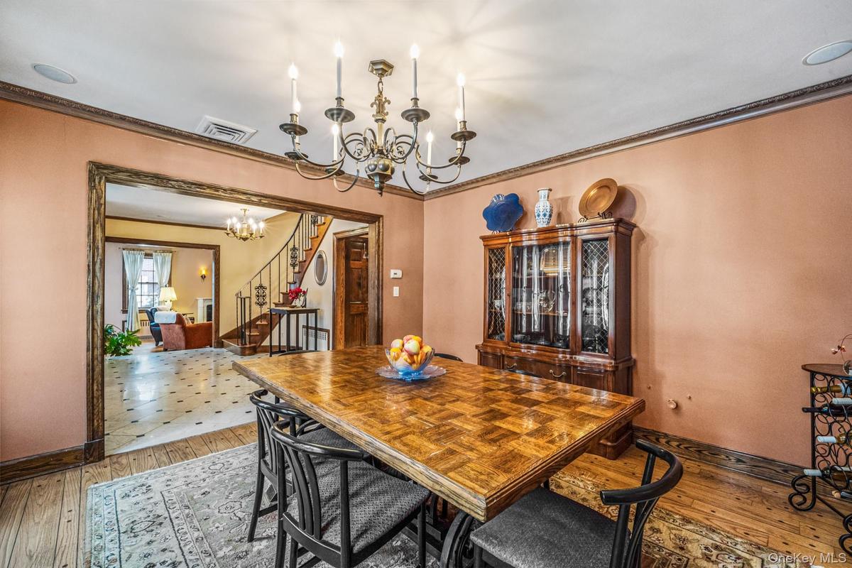 Dining area featuring a chandelier, stairs, light wood-style flooring, and ornamental molding