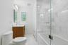 Beautifully renovated with timeless marble finishes, the hall bath features a sleek glass-enclosed tub and shower, custom vanity, and sophisticated fi