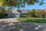 View of front of property featuring driveway, a front yard, a garage, and a shingled roof