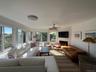 Living room featuring a glass covered fireplace, a ceiling fan, and wood finished floors
