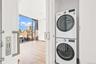 Washroom with estacked washer and dryer, expansive windows, and light wood-type flooring