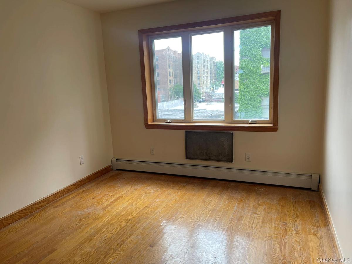 Empty room featuring a baseboard heating unit and wood finished floors