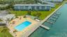 This aerial view highlights the expansive pool deck, clubhouse, deck shuffleboard courts and boat docks
