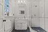 Full bath featuring vanity, a stall shower, wainscoting, tile walls, and detailed molding.