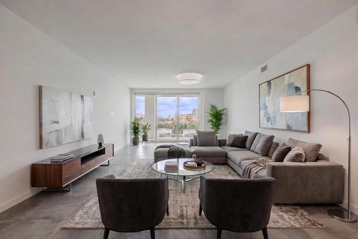This bright and spacious dining and living area offers an elegant, open layout with sleek tile flooring and contemporary lighting. Floor-to-ceiling gl