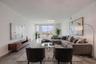 This bright and spacious dining and living area offers an elegant, open layout with sleek tile flooring and contemporary lighting. Floor-to-ceiling gl