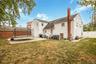 Rear view of property featuring a patio, a gate, a trampoline, a chimney, and a shingled roof