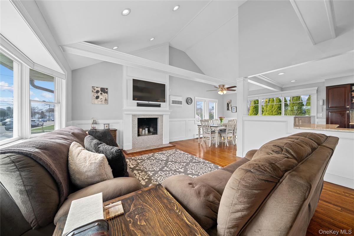 Living room with a wainscoted wall, wood finished floors, a decorative wall, lofted ceiling, and recessed lighting