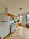 Kitchen featuring white appliances, radiator, light countertops, brown cabinetry, and an ornate ceiling