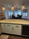 Kitchen with wine cooler, white cabinets, pendant lighting, and light stone countertops