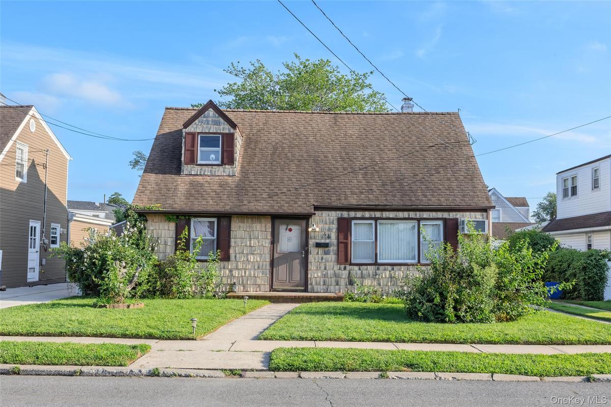 Front facade featuring shingle siding, a dormer window, and a gabled roof