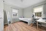 Bedroom with radiator heating unit, light wood-style floors, crown molding