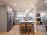 Kitchen with a tiled fireplace, high quality appliances, pendant lighting, light wood finished floors, and a kitchen breakfast bar