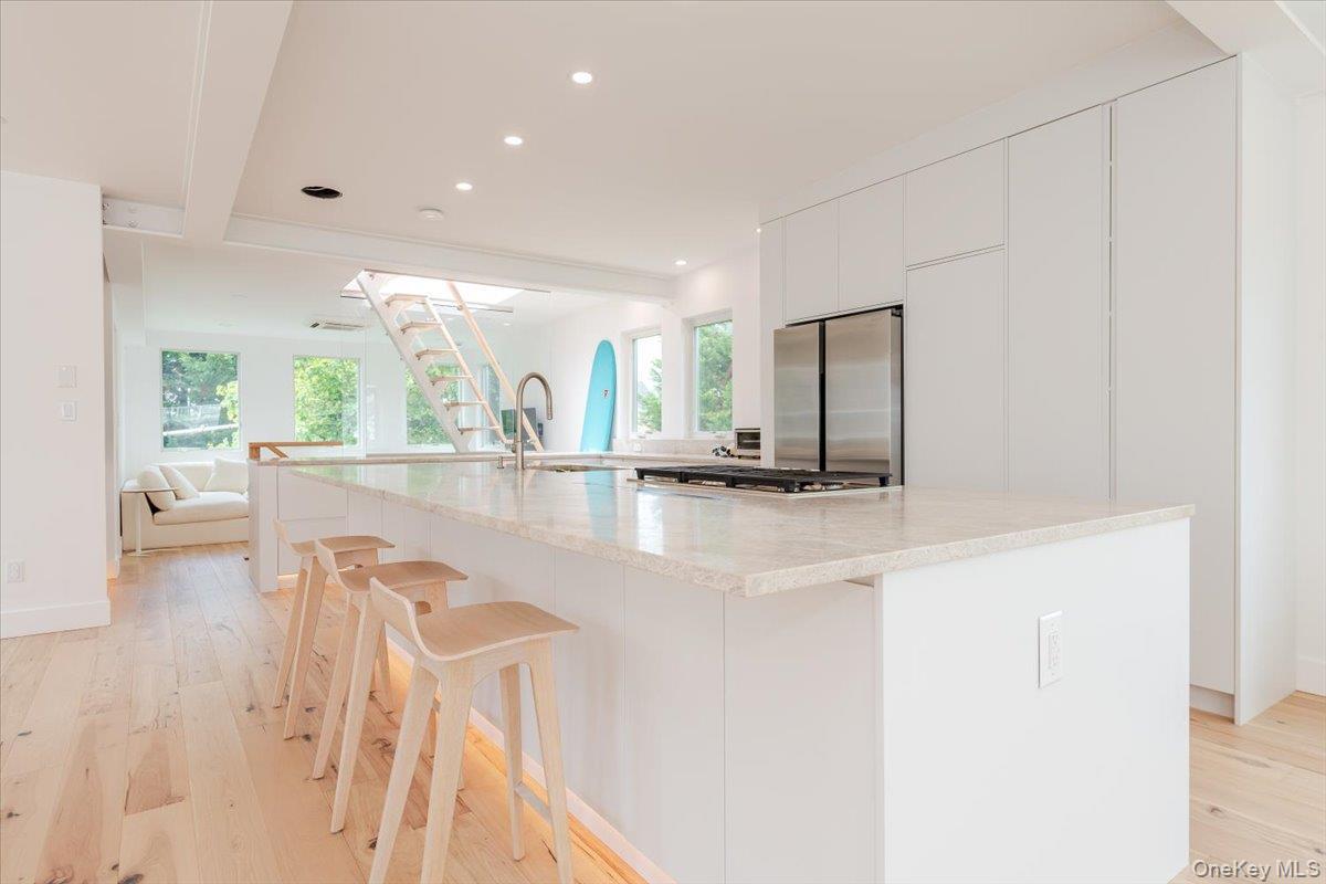 Kitchen featuring stainless steel fridge, recessed lighting, open floor plan, light wood-style flooring, and a spacious island