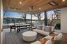 Patio terrace at dusk with outdoor lounge area, ceiling fan, exterior kitchen, grilling area, and a water view