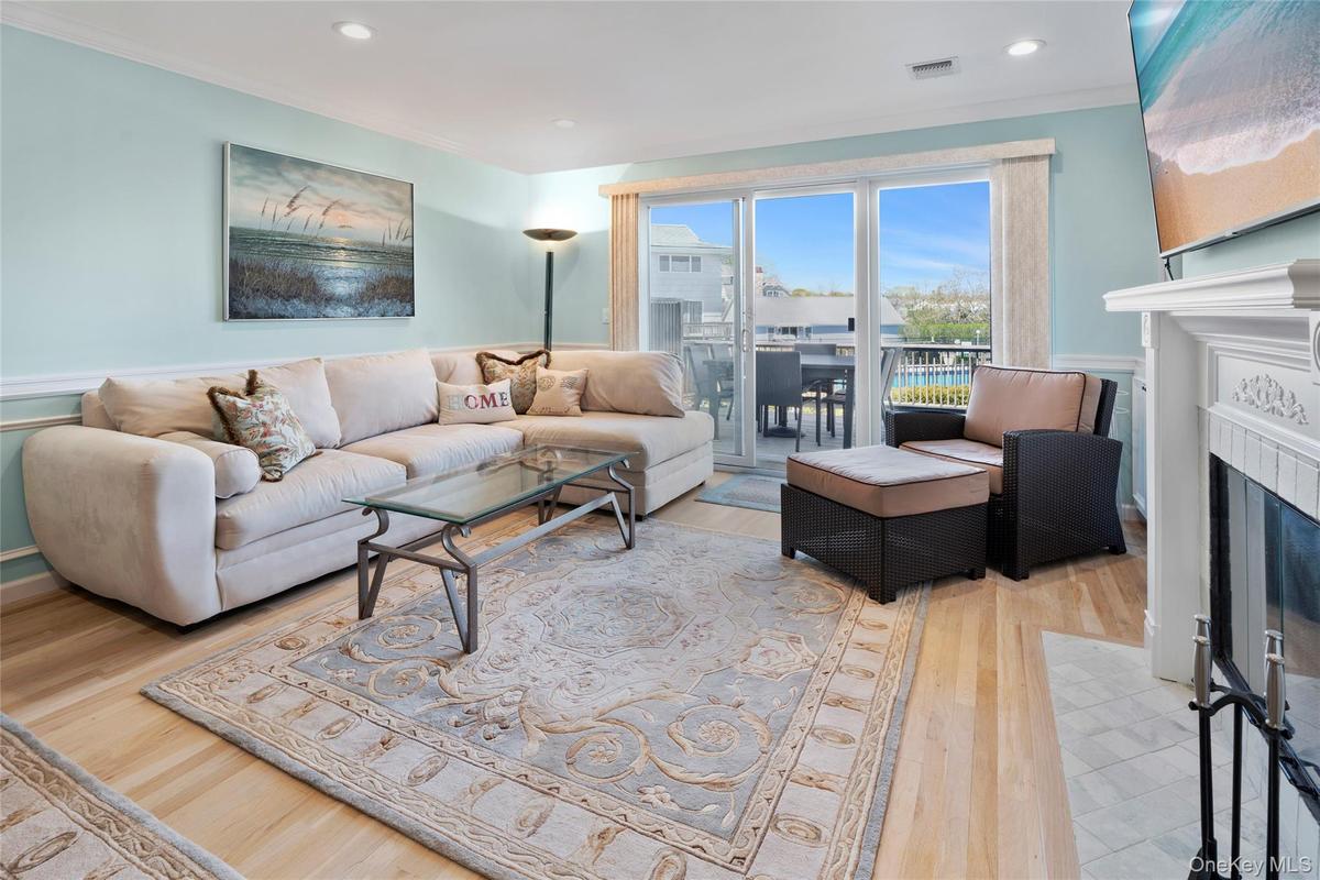Living area with a fireplace with flush hearth, recessed lighting, wood finished floors, visible vents, and crown molding
