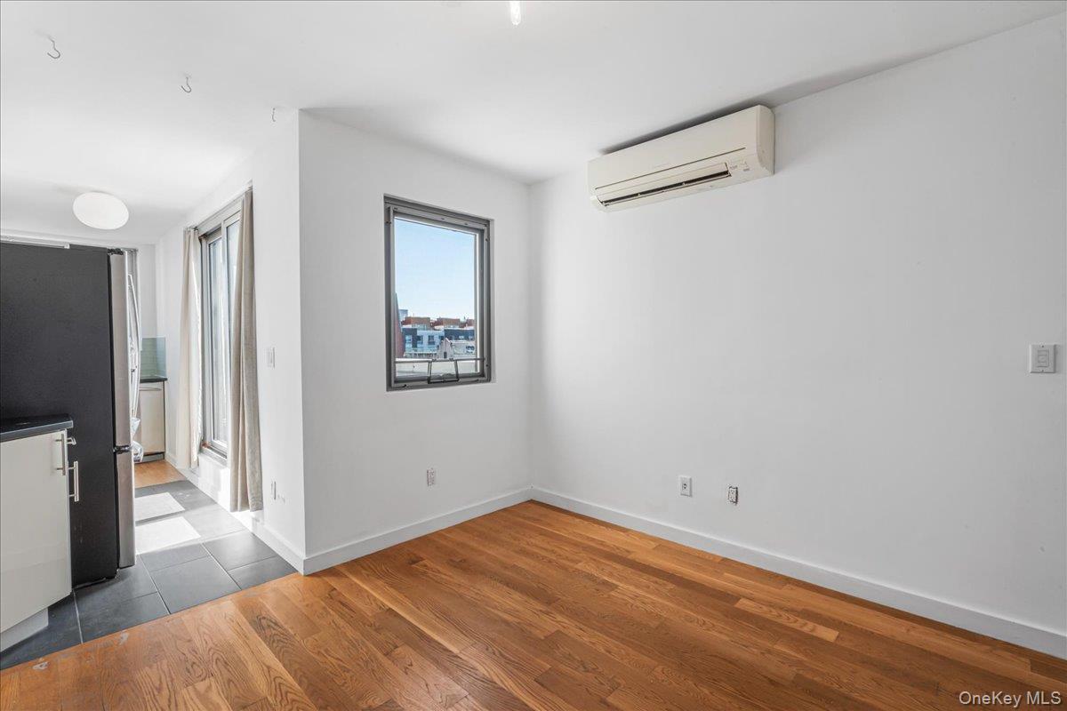 Unfurnished dining area featuring wood finished floors and a wall mounted air conditioner