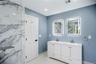 Modern en-suite bathroom featuring a double vanity with white cabinetry and integrated sinks, illuminated by two LED mirrors