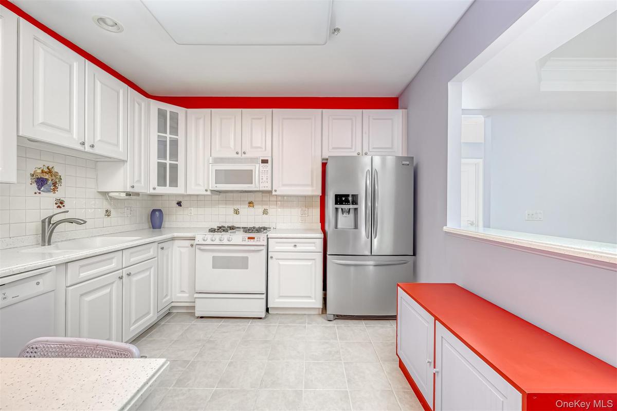Kitchen featuring white appliances, backsplash, glass insert cabinets, white cabinets, and light tile patterned flooring