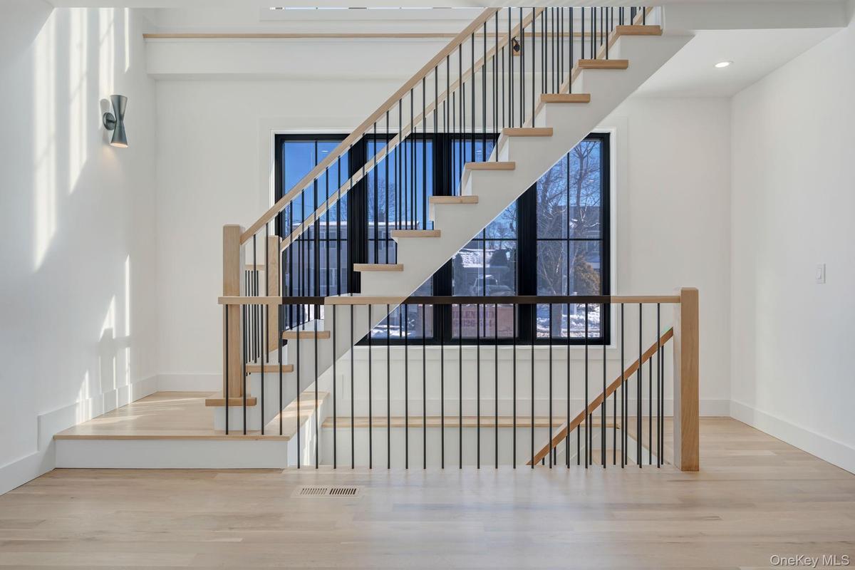 Striking staircase with modern railing and large window wall that brings light into both levels and adds architectural character.
