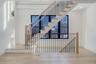 Striking staircase with modern railing and large window wall that brings light into both levels and adds architectural character.