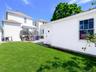 Private backyard featuring a well-maintained lawn, a wooden deck, and a stucco-finished outbuilding with a single window. ai generated