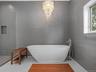 Bathroom with tile walls, a freestanding bath, a walk in shower, and a chandelier
