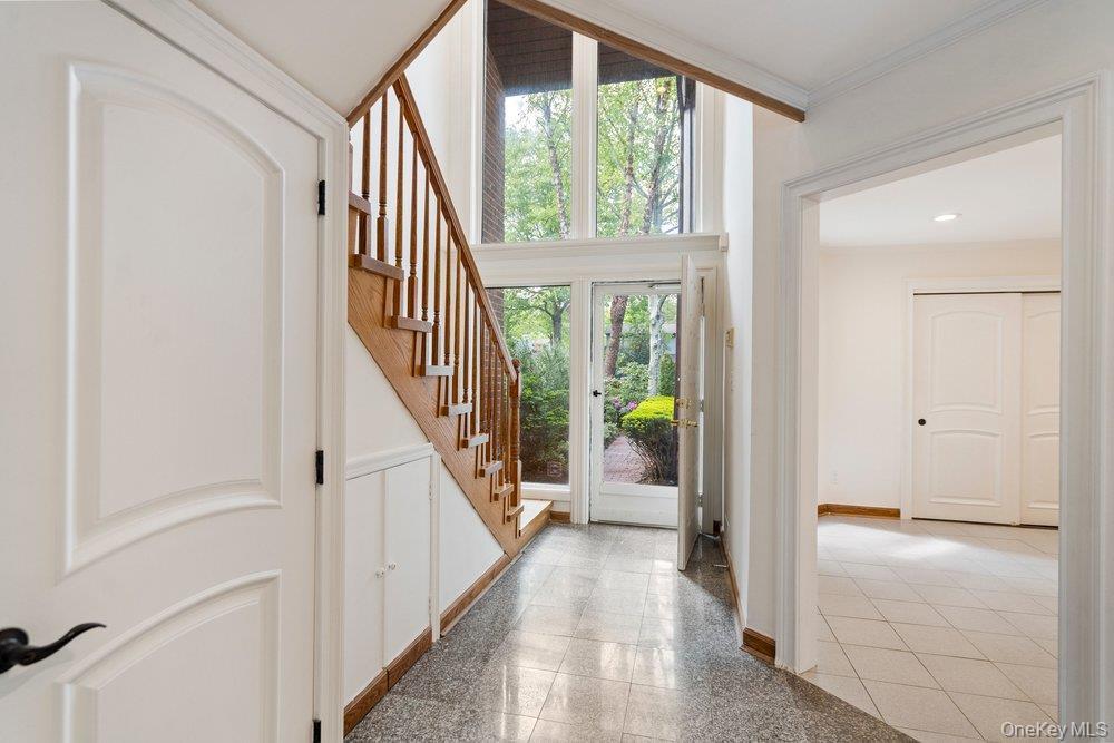 Foyer featuring a grand staircase with wood treads and railings, expansive floor-to-ceiling windows, and a tiled floor