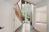 Foyer featuring a grand staircase with wood treads and railings, expansive floor-to-ceiling windows, and a tiled floor