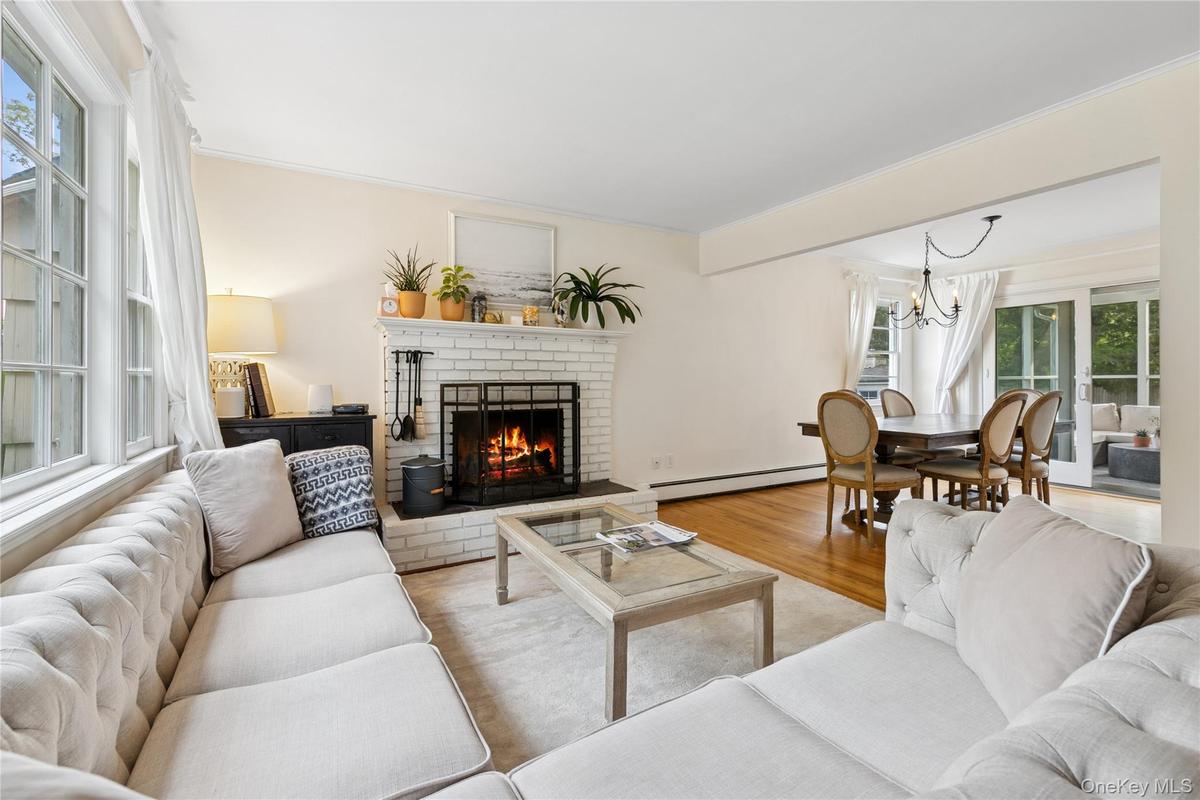 Living room with a fireplace, wood finished floors, baseboard heating, a chandelier, and ornamental molding