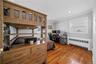 Bedroom with crown molding, radiator, an office area, freestanding refrigerator, and dark wood finished floors