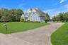 Shingle-sided exterior with multiple gables, an attached two-car garage, a paved driveway, and a spacious lawn