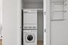 Dedicated laundry closet featuring a stacked white washer and dryer unit