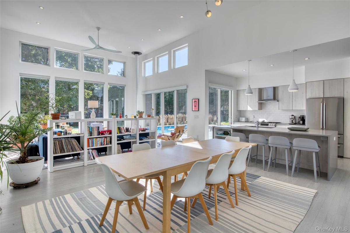 Dining room with ceiling fan, light hardwood / wood-style flooring, a towering ceiling, and sink