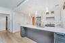 Kitchen featuring white cabinetry, decorative backsplash, pendant lighting, light wood-style flooring, and stainless steel appliances