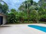 Curved swimming pool with a surrounding concrete deck, mature palm trees, and established tropical landscaping