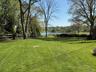Expansive lawn featuring mature trees and a split rail fence