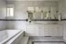 Bathroom with tile walls, a bath, double vanity, inlaid floor details, and a stall shower