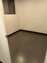 Compact room featuring light-colored walls, dark baseboards, and a window with a dark frame
