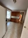 Kitchen featuring brown cabinetry, decorative backsplash, refrigerator, and light tile patterned floors