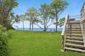 View of grassy yard with stairway and a water view