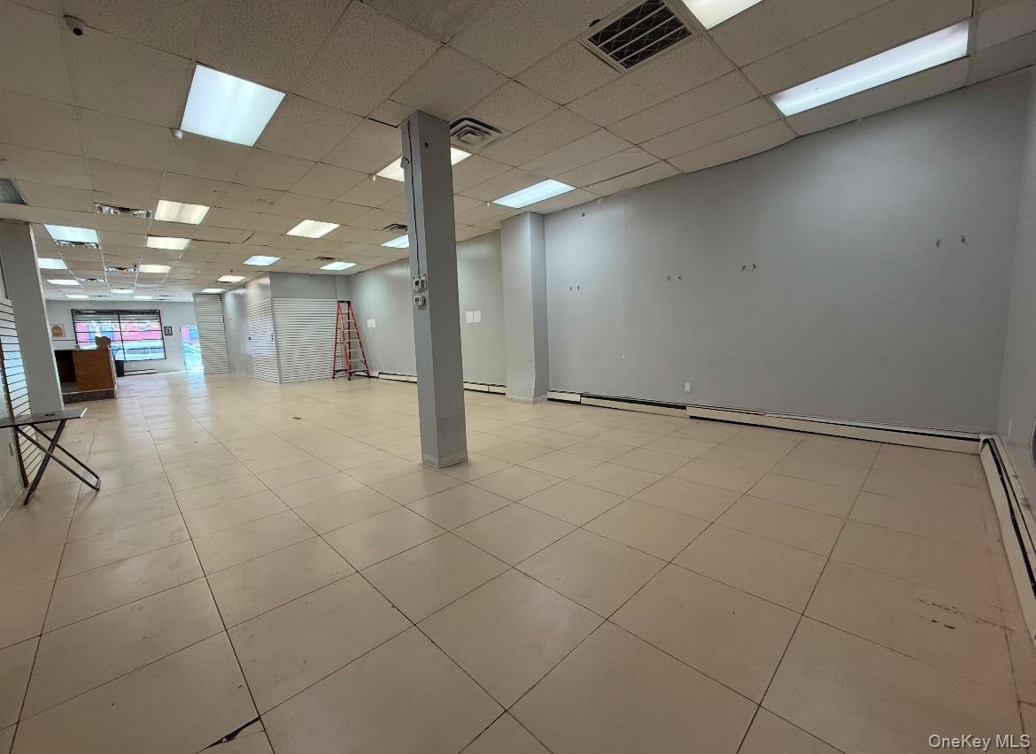 Basement featuring a drop ceiling and a baseboard heating unit