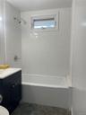 Bathroom featuring bathing tub / shower combination, stone finish floors, and vanity