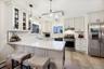 Kitchen featuring stainless steel appliances, light stone countertops, a peninsula, and white cabinetry