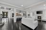 Living area with a glass covered fireplace, recessed lighting, dark wood-style floors, crown molding, and stairway
