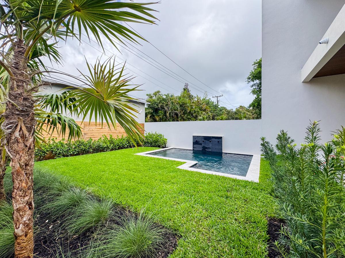 (as of April 8, 2026) view of spa pool and backyard from patio, clusia grows quickly and will be taller than fence by end of year