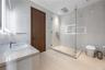 Modern guest bathroom with full-height white marble tile walls and floors, frameless glass walk-in shower, illuminated recessed niche, multi-function