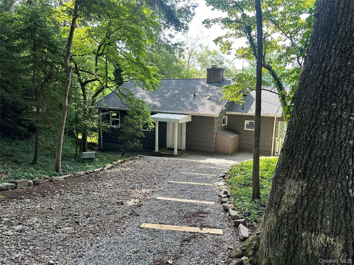 Rear view of house featuring a shingled roof and a chimney
