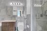 Bathroom featuring tile walls, vanity, and a marble finish shower